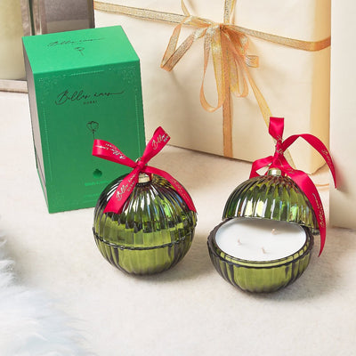 two green baubles with red ribbon behind it a white gift box with some gold ribbon, green packaging